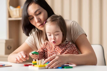 Mother plays with toys with her special needs daughter
